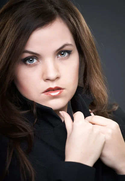 Portret van aantrekkelijke jonge vrouw in een zwarte jas. Close-up. — Stockfoto