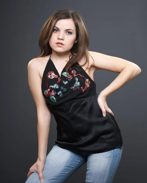 Attractive young woman in a black blouse and blue jeans. — Stock Photo, Image
