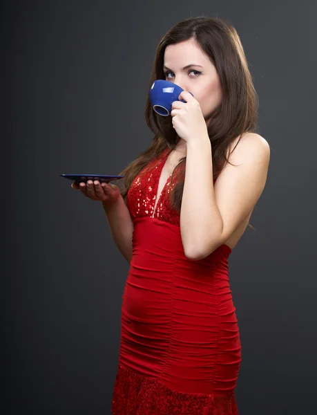 Attraente giovane donna con un vestito rosso. Donna che beve da un blu — Foto Stock