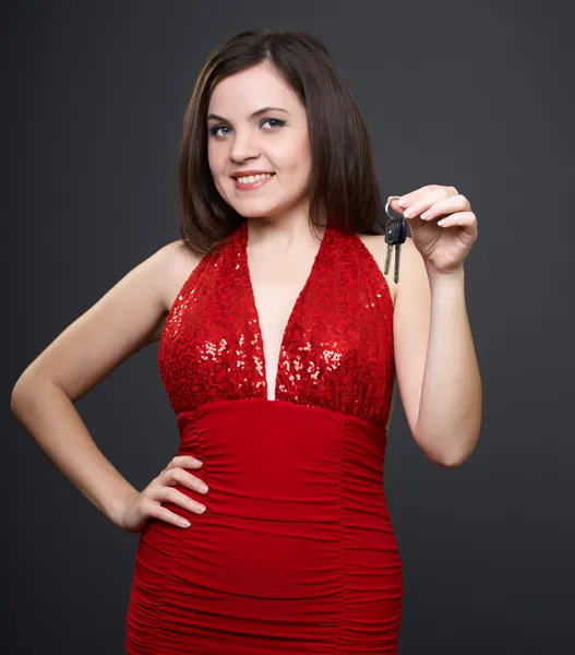 Feliz joven con el vestido rojo. Mujer sostiene las llaves en su —  Fotos de Stock