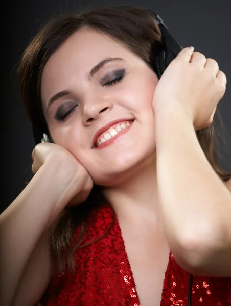 Glückliche junge Frau im roten Kleid. Frau hört Musik auf — Stockfoto