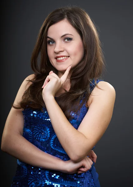 Happy young woman in a blue dress. Woman holds her finger on her — Stock Photo, Image