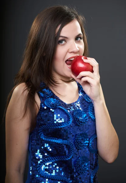 Uma jovem atraente num vestido azul. Mulher mordendo uma maçã vermelha — Fotografia de Stock