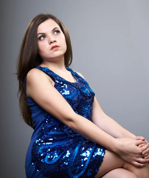 Attractive young woman in a blue shiny dress. Woman sitting and — Stock Photo, Image