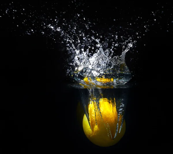 Limão amarelo fresco caindo na água com um toque de água — Fotografia de Stock