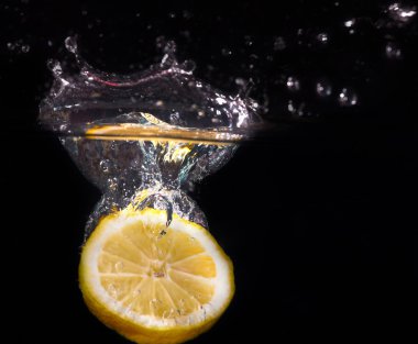su bir sıçrama ile suya düşen sarı taze limon