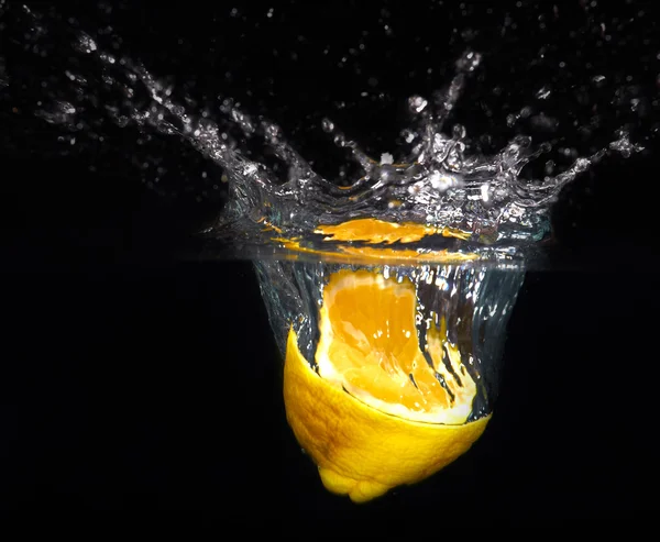 Fresh yellow lemon falling into the water with a splash of water — Stock Photo, Image