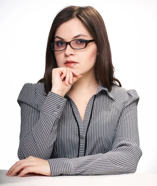 Attractive young woman in a gray blouse and glasses sitting at t — Stock Photo, Image