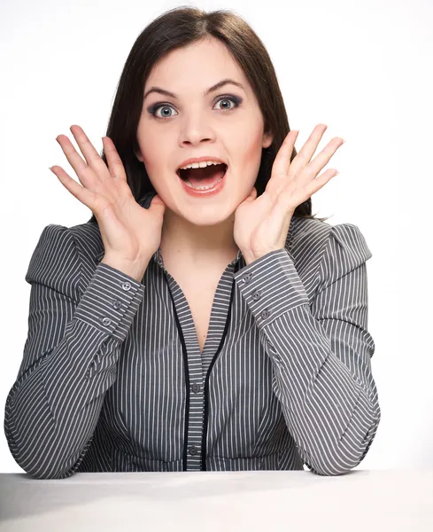 Verrast jonge vrouw in een grijze blouse zitten aan de tafel. — Stockfoto