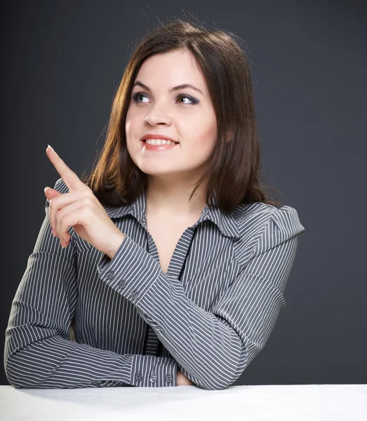 Attraktive junge Frau in grauer Bluse, die am Tisch sitzt. wo — Stockfoto
