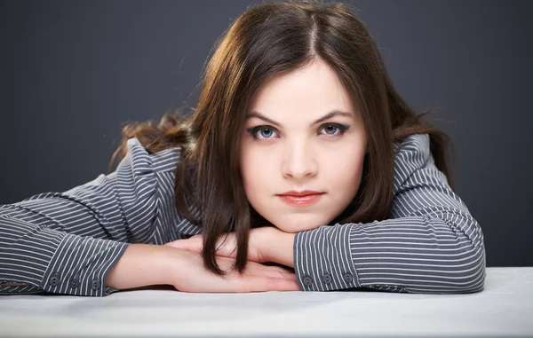 Attractive young woman in a gray blouse sitting at the table. — Stock Photo, Image