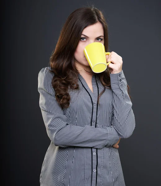 Attractive young woman in a gray shirt. Woman drinking from a ye — Stock Photo, Image