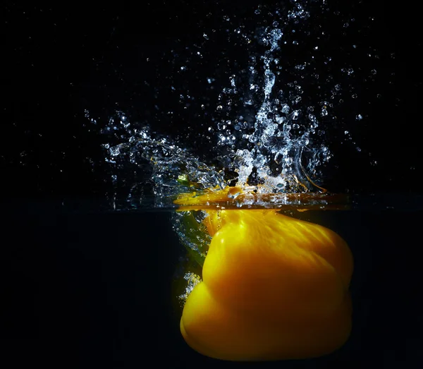 Свежая желтая паприка падает в воду с брызгами вата — стоковое фото