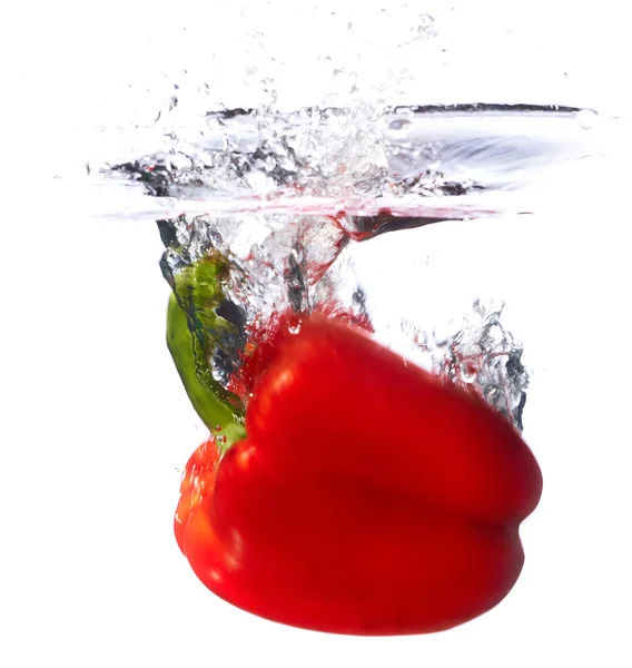 Färsk röd paprika faller i vattnet med ett stänk av vatten. — Stockfoto