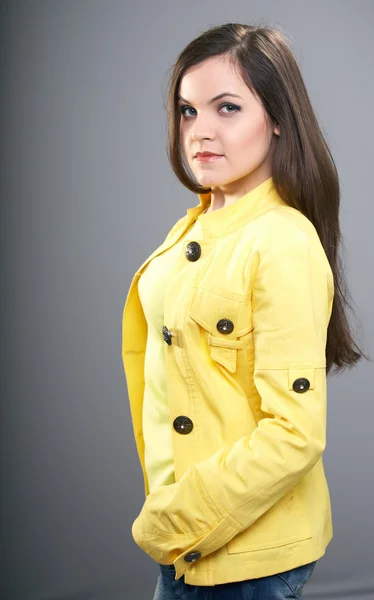 Aantrekkelijke jonge vrouw in een gele jas. — Stockfoto