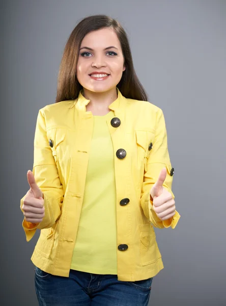 Glad ung kvinna i gul jacka. kvinnan visar tummen upp. — Stockfoto
