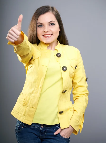 Happy young woman in yellow jacket. Woman shows thumbs up. — Stock Photo, Image