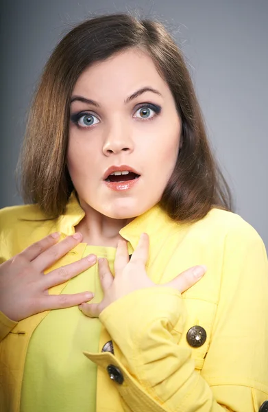 Surpreendida jovem mulher em uma jaqueta amarela . — Fotografia de Stock