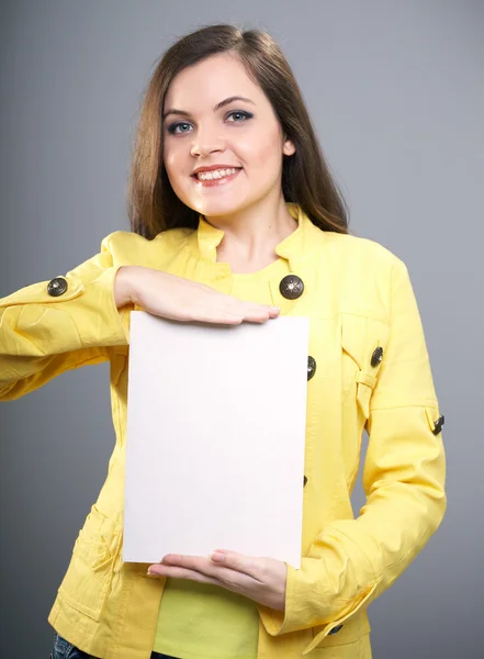 Aantrekkelijke jonge vrouw in een gele jas. vrouw houdt een poster. — Stockfoto