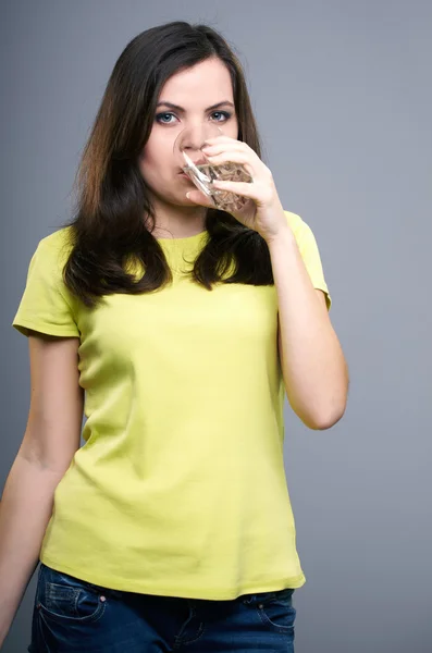 Una joven atractiva con una camisa amarilla. Mujer bebiendo mineral —  Fotos de Stock