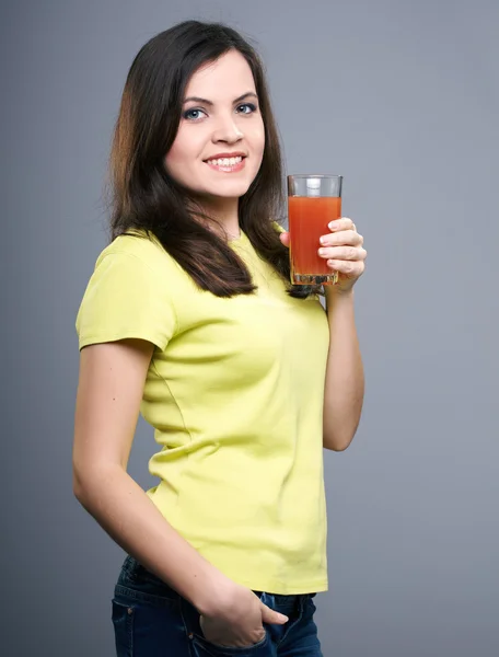 Happy young woman in a yellow shirt. Woman holds a glass of juic — Stock Photo, Image