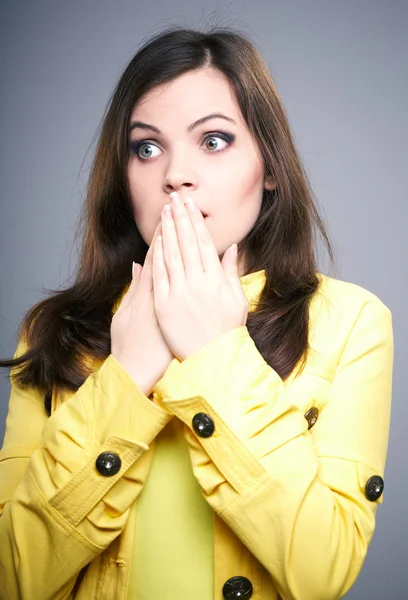 Überraschte junge Frau in gelber Jacke. Blick nach rechts. — Stockfoto