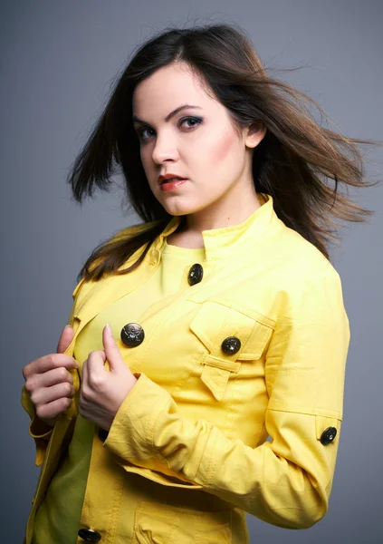 Uma jovem atraente com um casaco amarelo. Cabelo em movimento . — Fotografia de Stock
