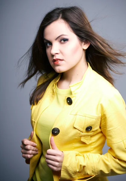 Attraktive junge Frau in gelber Jacke. Haare in Bewegung. — Stockfoto