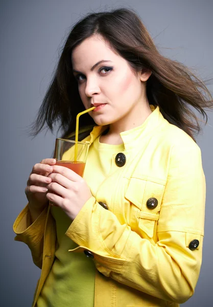 Attraktive junge Frau in gelber Jacke. Frau trinkt Saft — Stockfoto