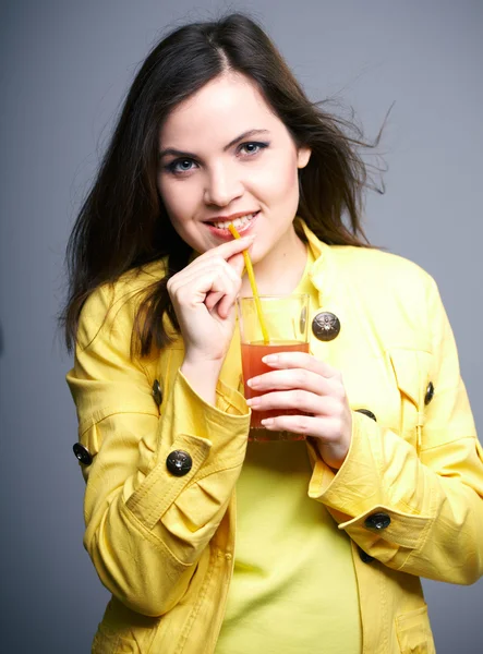Attraktive junge Frau in gelber Jacke. Frau trinkt Saft. — Stockfoto
