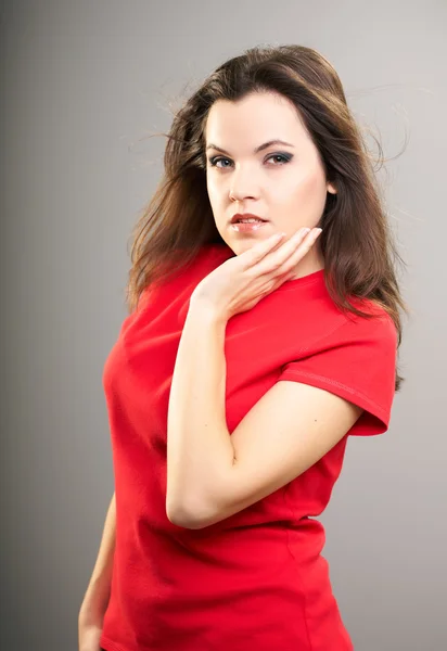 Attractive young woman in a red shirt. Hair in motion. — Stock Photo, Image