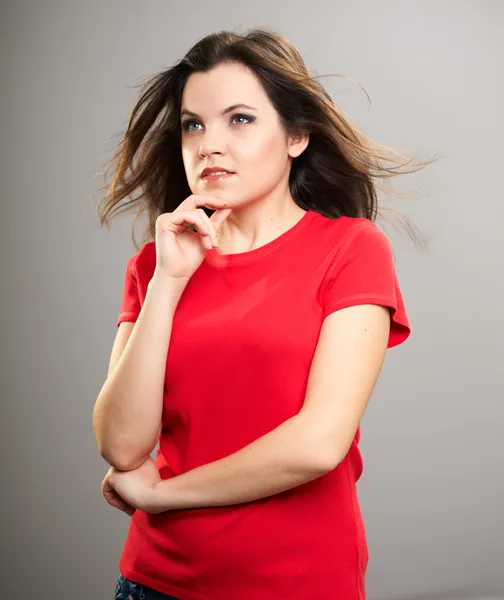 Uma jovem atraente com uma camisa vermelha. Mulher pensa e olhando — Fotografia de Stock