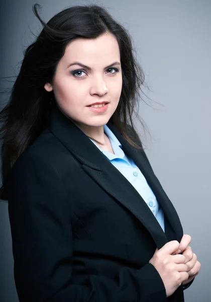 Uma jovem atraente com um casaco preto. Cabelo em movimento . — Fotografia de Stock