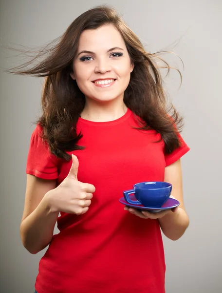 Attractive young woman in a red shirt. Woman holds a blue cup an — Stock Photo, Image