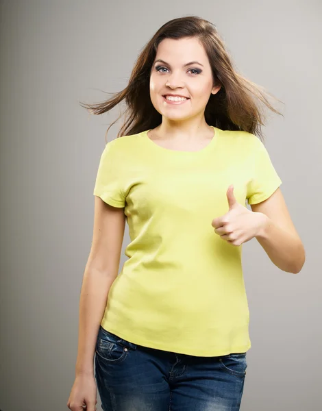 Una joven feliz con una camisa amarilla. Mujer mostrando pulgares hacia arriba . —  Fotos de Stock