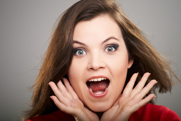 Удивлённая молодая женщина в красной рубашке. Волосы в движении
.