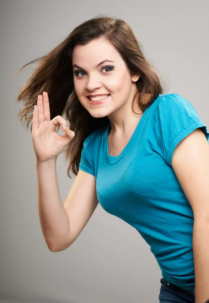 Una joven atractiva con una camisa azul. Mujer muestra una señal bien . — Foto de Stock