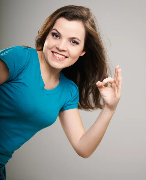 Attractive young woman in a blue shirt. Woman shows a sign okay. — Stock Photo, Image