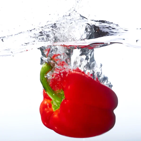 Paprika merah segar jatuh ke dalam air dengan percikan air — Stok Foto