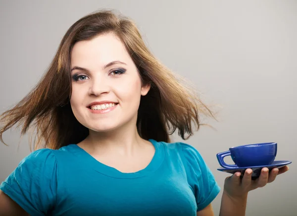 Una joven atractiva con una camisa azul. Una mujer sosteniendo una c azul — Foto de Stock