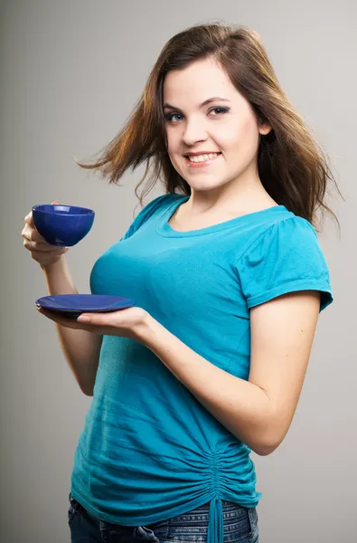 Attractive young woman in a blue shirt. A woman holding a blue c — Stock Photo, Image