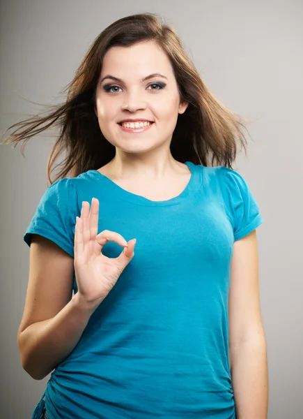 Attraktive junge Frau im blauen Hemd. Frau zeigt ein Zeichen in Ordnung. — Stockfoto