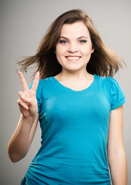 Jovem feliz de camisa azul. Mulher mostra um símbolo de victo — Fotografia de Stock