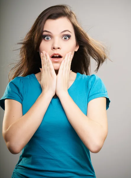 Verrast jonge vrouw in een blauw shirt. haar in beweging. — Stockfoto