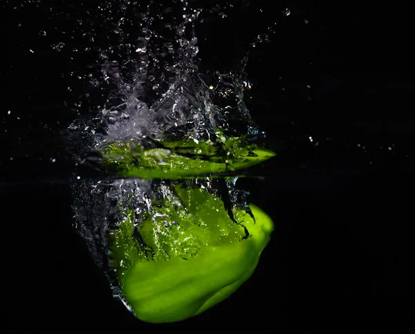 Páprica verde fresca caindo na água com um toque de água — Fotografia de Stock