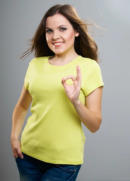 Uma jovem atraente com uma camisa amarela. Mulher mostra um sinal oka — Fotografia de Stock