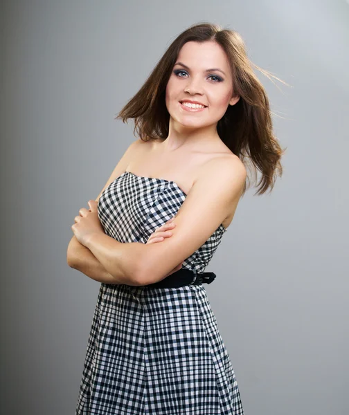 Attractive young woman in a plaid dress. Hair in motion. — Stock Photo, Image