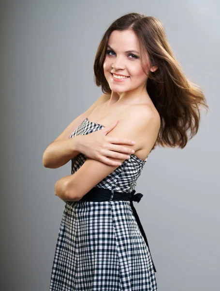 Attractive young woman in a plaid dress. Hair in motion. — Stock Photo, Image