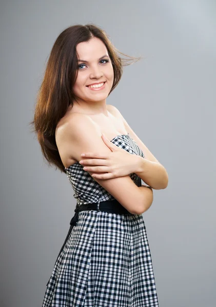 Happy young woman in a checkered dress. Hair in motion. — Stock Photo, Image