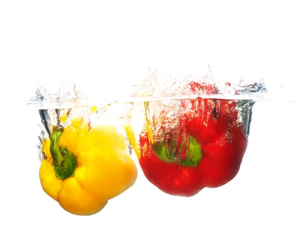 Zwei frische Paprika, die mit einem Spritzer Wasser ins Wasser fallen. — Stockfoto